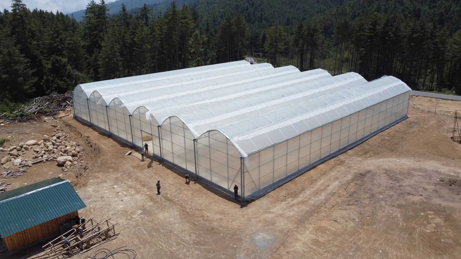 An aerial view of the MaMaKyiJong greenhouse surrounded by trees and hills